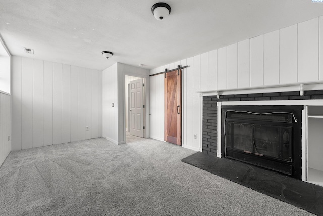 unfurnished living room with a barn door and carpet floors