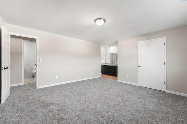 unfurnished bedroom featuring ensuite bathroom and carpet floors