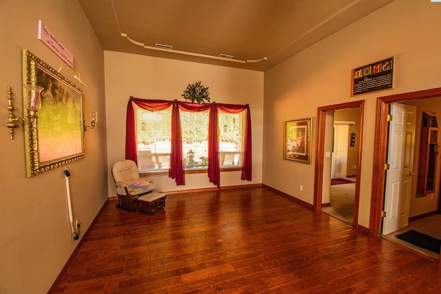 sitting room with wood-type flooring, visible vents, and baseboards