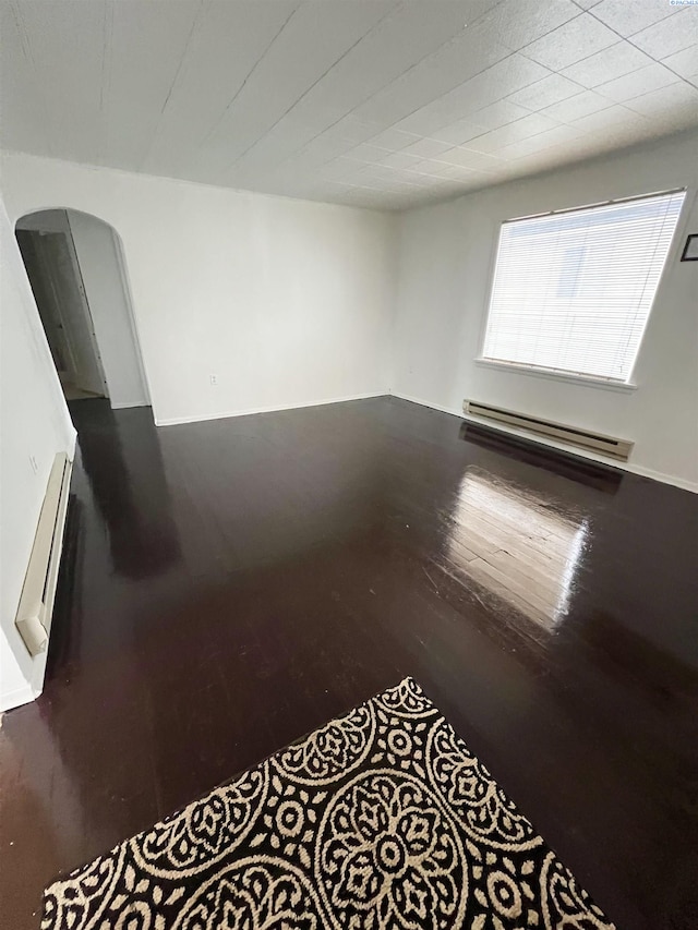 empty room with a baseboard heating unit and hardwood / wood-style flooring