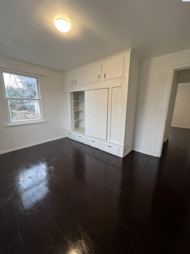 unfurnished bedroom with dark wood-type flooring, a textured ceiling, and a closet