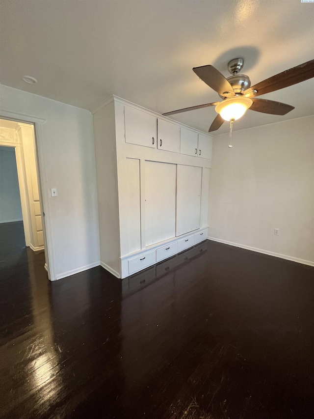 unfurnished bedroom featuring ceiling fan and dark wood-type flooring