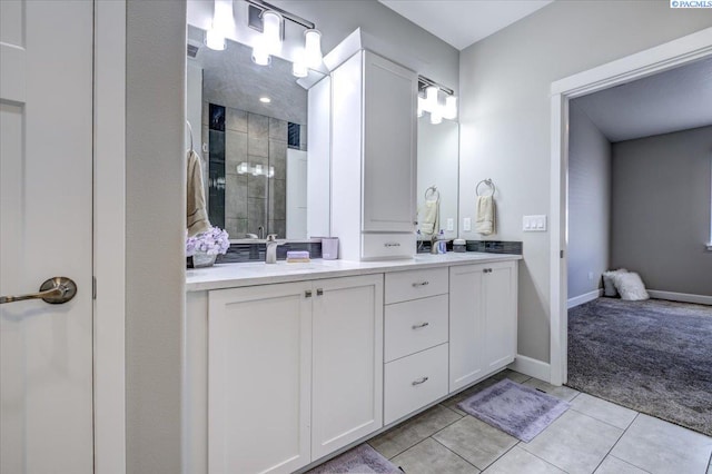 bathroom with tile patterned flooring, double vanity, baseboards, a shower stall, and a sink