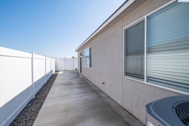 view of property exterior featuring cooling unit, a fenced backyard, a patio area, and stucco siding