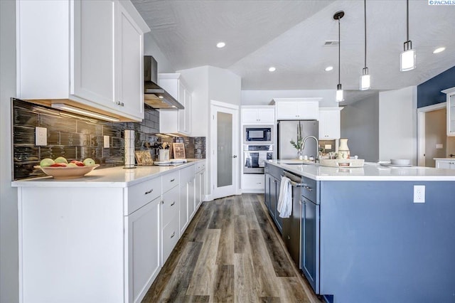 kitchen with dark wood-style flooring, an island with sink, wall chimney exhaust hood, white cabinetry, and appliances with stainless steel finishes
