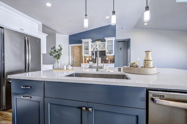 kitchen featuring lofted ceiling, white cabinets, a sink, appliances with stainless steel finishes, and decorative light fixtures