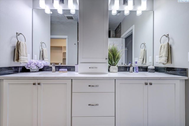 full bathroom with double vanity, a sink, and visible vents