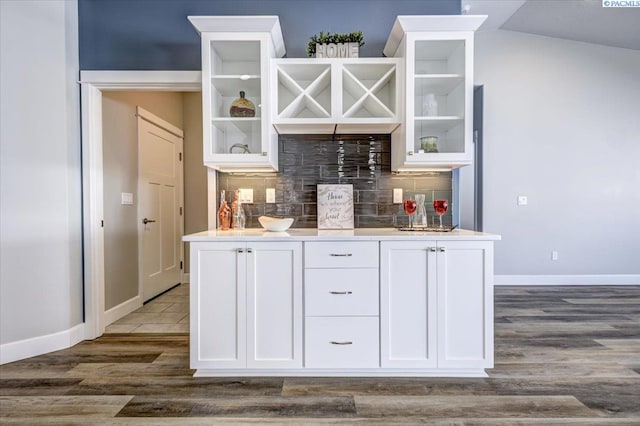 bar with baseboards, a dry bar, dark wood finished floors, and tasteful backsplash