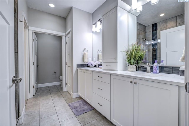full bathroom with double vanity, tile patterned flooring, a sink, toilet, and tiled shower