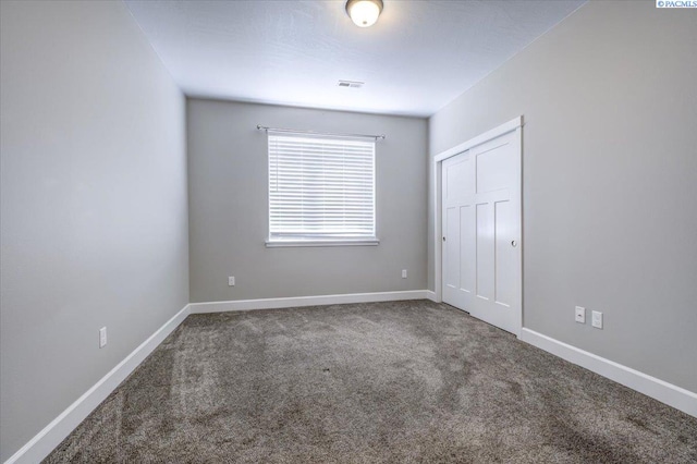 unfurnished bedroom featuring baseboards, carpet flooring, visible vents, and a closet