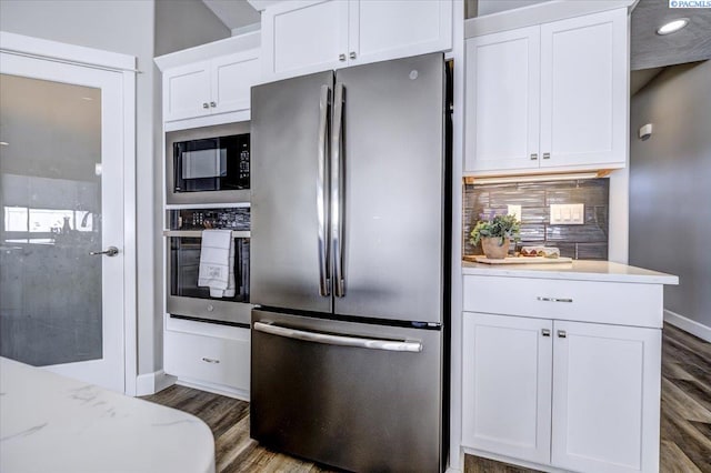 kitchen featuring wood finished floors, baseboards, white cabinets, appliances with stainless steel finishes, and backsplash