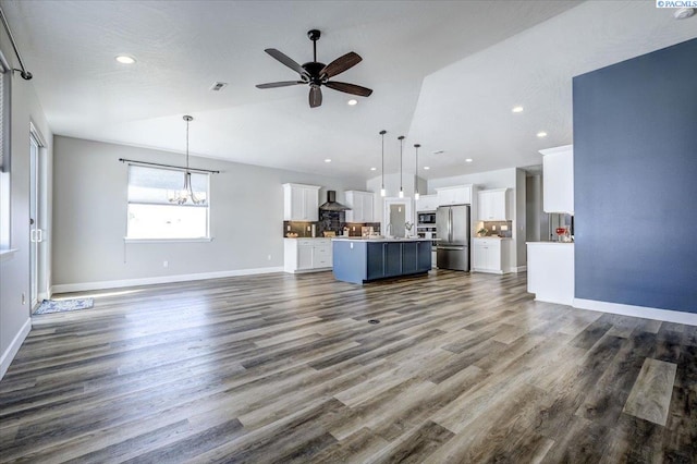 unfurnished living room featuring recessed lighting, dark wood-style flooring, ceiling fan with notable chandelier, and baseboards