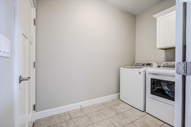 washroom featuring baseboards, cabinet space, light tile patterned flooring, and washer and dryer