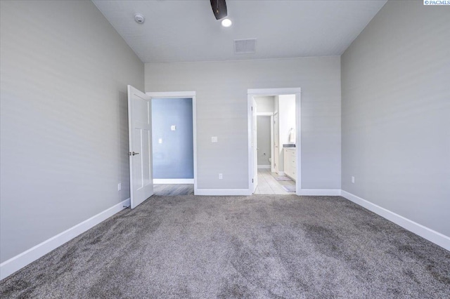 unfurnished bedroom with carpet flooring, baseboards, visible vents, and connected bathroom