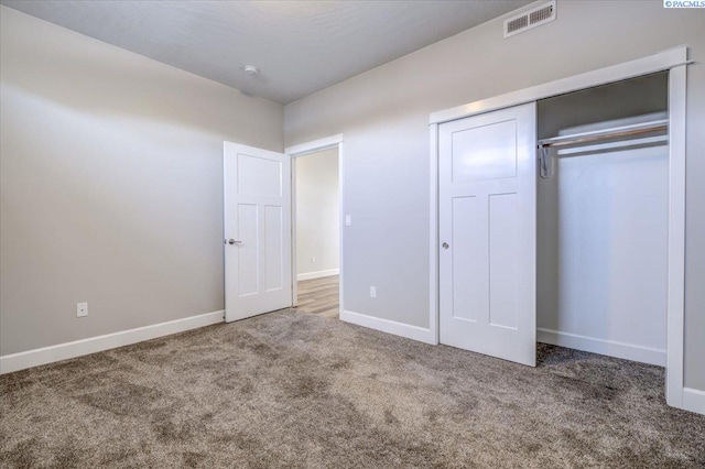 unfurnished bedroom featuring visible vents, carpet, baseboards, and a closet