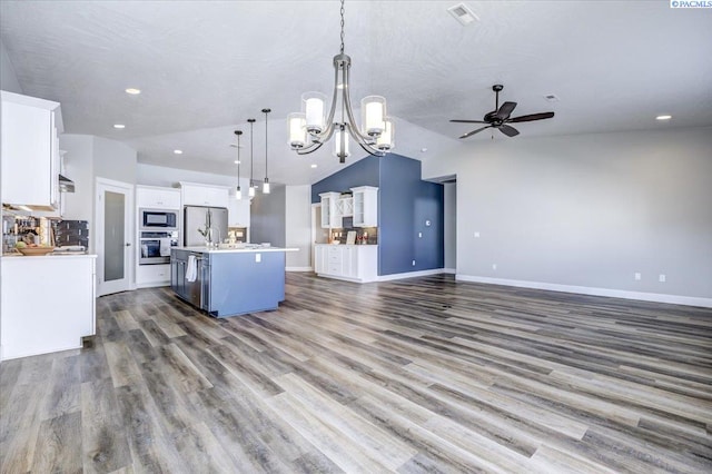 kitchen with appliances with stainless steel finishes, a kitchen island with sink, ceiling fan with notable chandelier, open floor plan, and lofted ceiling