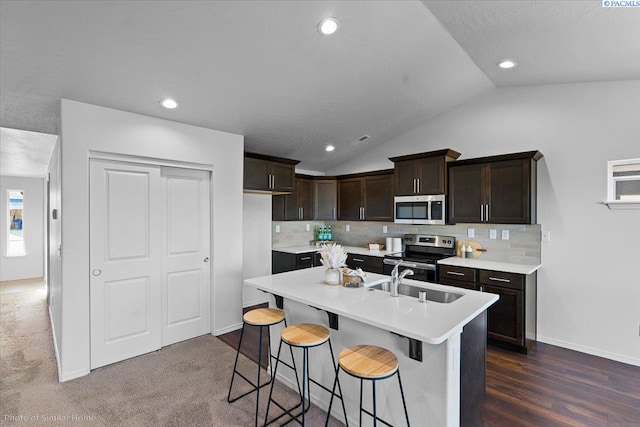 kitchen featuring vaulted ceiling, appliances with stainless steel finishes, sink, a kitchen breakfast bar, and a kitchen island with sink