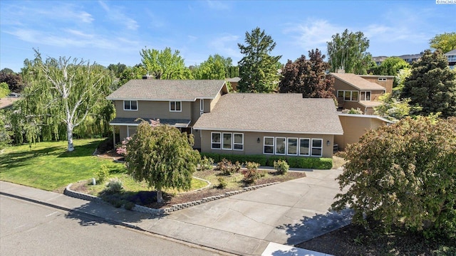 view of front of home featuring concrete driveway, a shingled roof, and a front yard