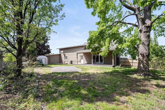 rear view of property with fence, a storage unit, an outdoor structure, cooling unit, and a patio