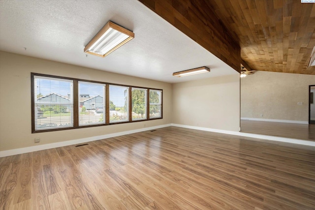 interior space with vaulted ceiling with beams, baseboards, visible vents, and wood finished floors