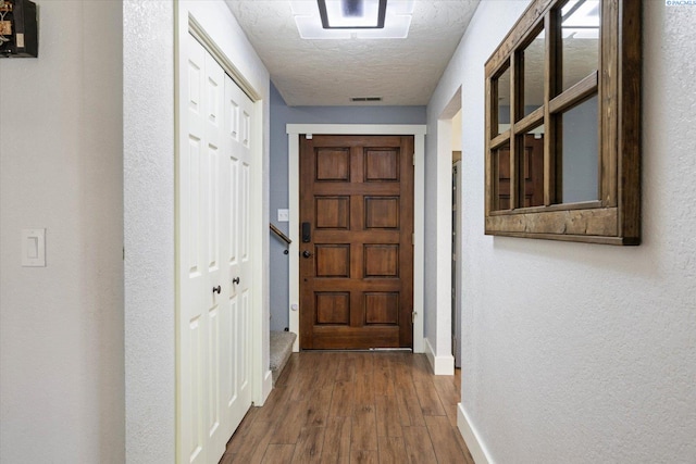 hallway featuring baseboards, a textured ceiling, and hardwood / wood-style floors