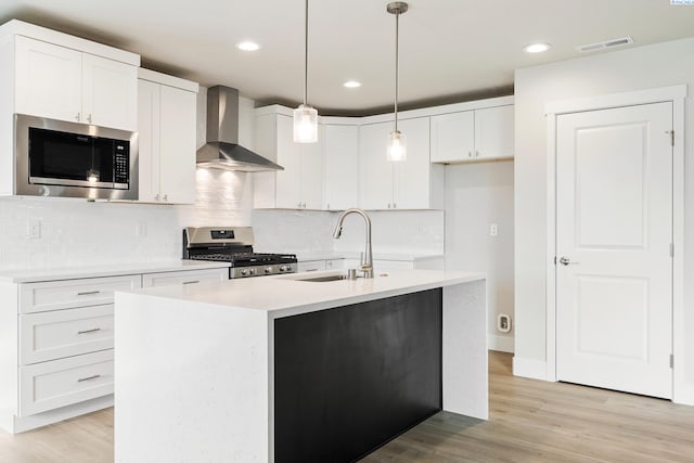 6531 W 30th Pl, Kennewick, WA 99338 - kitchen with wall chimney range hood, stainless steel appliances, white cabinets, light wood finished floors, and tasteful backsplash