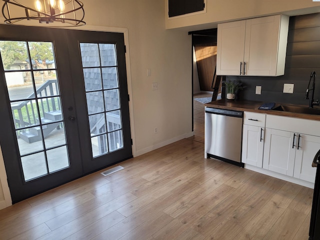 kitchen featuring pendant lighting, sink, dishwasher, white cabinets, and french doors