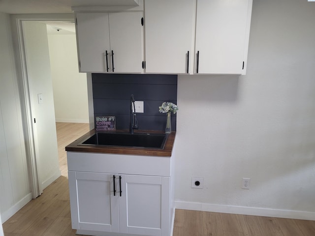 kitchen featuring sink, white cabinets, and light wood-type flooring