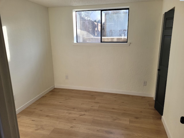 unfurnished room with light hardwood / wood-style flooring and a textured ceiling