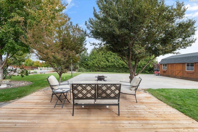 wooden deck featuring a fire pit, a yard, a shed, and an outdoor structure