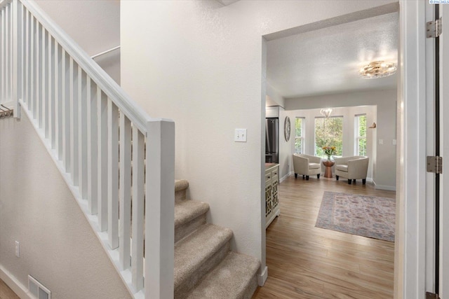 stairway featuring visible vents, a textured ceiling, baseboards, and wood finished floors