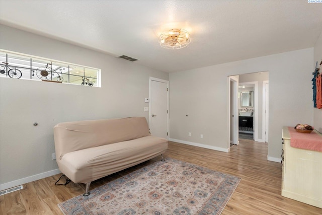 sitting room featuring light wood-style flooring, visible vents, and baseboards