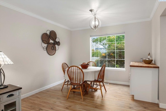 dining room with light wood finished floors, baseboards, and crown molding