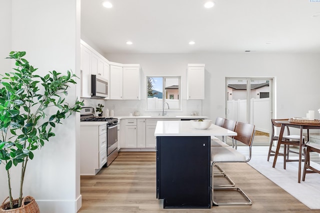 kitchen with a kitchen island, recessed lighting, light countertops, a sink, and appliances with stainless steel finishes