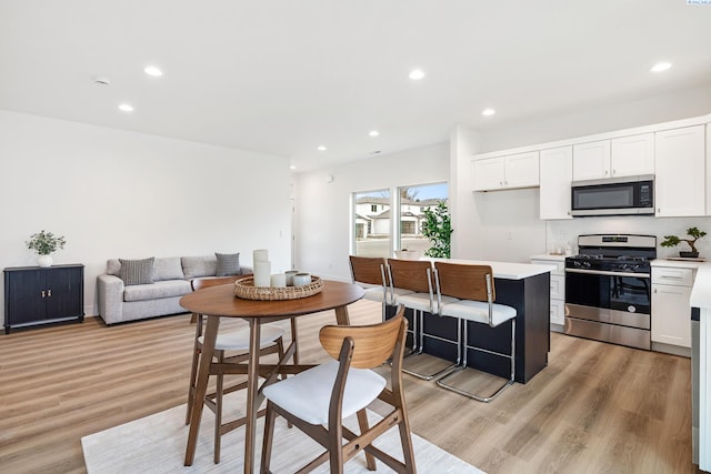kitchen with light countertops, stainless steel appliances, white cabinetry, and light wood finished floors