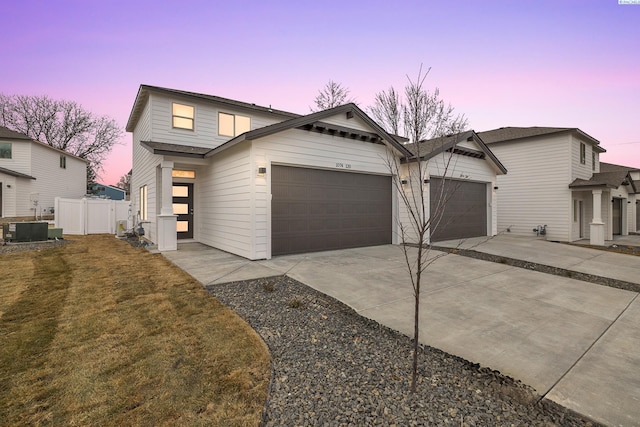 traditional home featuring a yard, central AC unit, a garage, fence, and concrete driveway