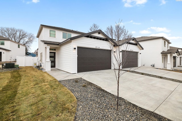 view of front of home featuring a front lawn, fence, cooling unit, concrete driveway, and an attached garage