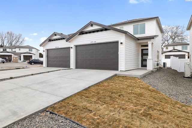 view of front facade featuring central air condition unit, fence, an attached garage, and driveway