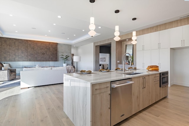 kitchen with sink, a center island with sink, hanging light fixtures, stainless steel dishwasher, and white cabinets