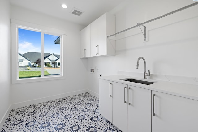 clothes washing area featuring electric dryer hookup, sink, hookup for a washing machine, and cabinets