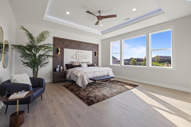 bedroom featuring light hardwood / wood-style flooring and a tray ceiling