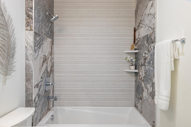 bathroom featuring tiled shower / bath combo and toilet