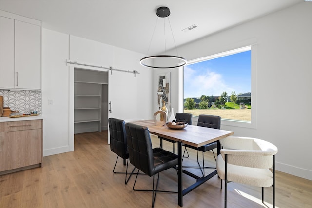 dining room with light hardwood / wood-style flooring and a barn door