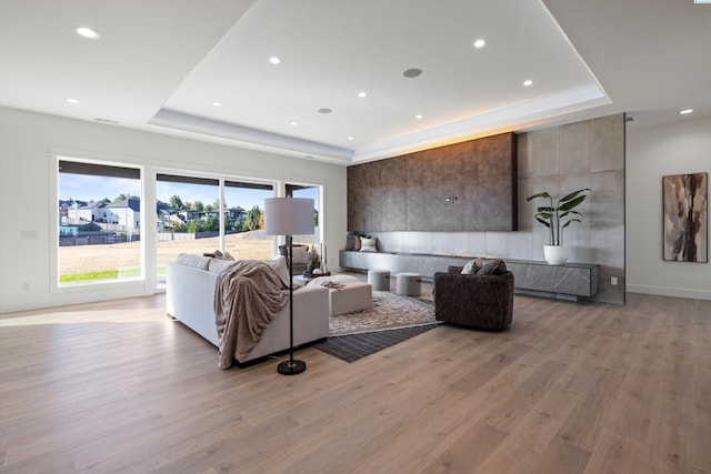 living room with a tray ceiling and light hardwood / wood-style floors