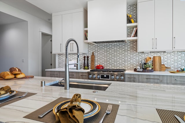 kitchen featuring decorative backsplash, white cabinets, light stone counters, and wall chimney exhaust hood