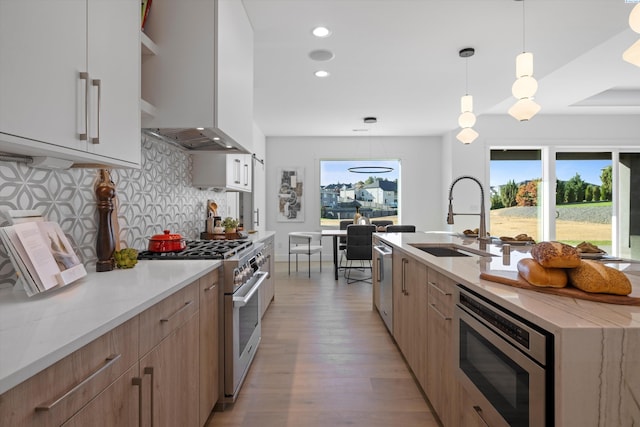 kitchen featuring pendant lighting, sink, stainless steel appliances, tasteful backsplash, and wall chimney exhaust hood