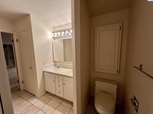 bathroom featuring vanity, a textured ceiling, tile patterned floors, and toilet