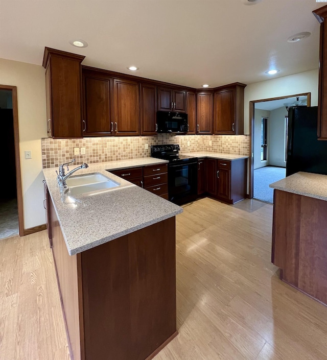 kitchen featuring tasteful backsplash, sink, black appliances, light stone countertops, and light hardwood / wood-style flooring