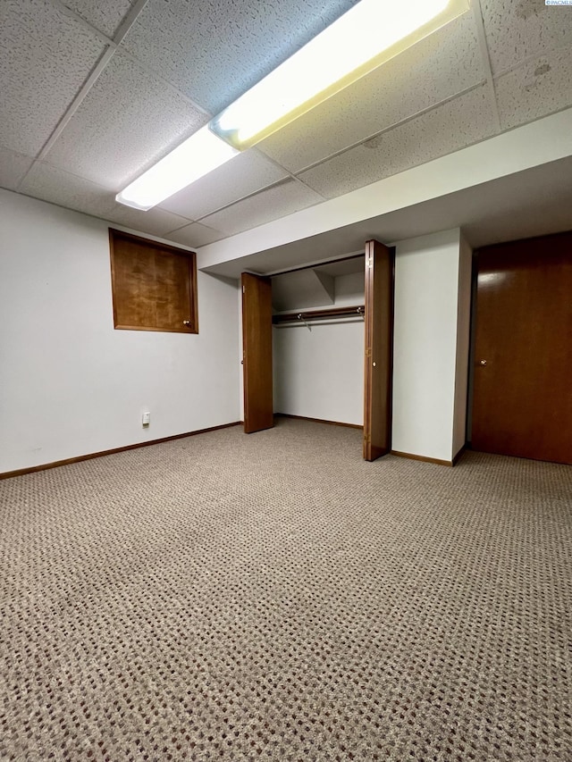 basement with a drop ceiling and carpet