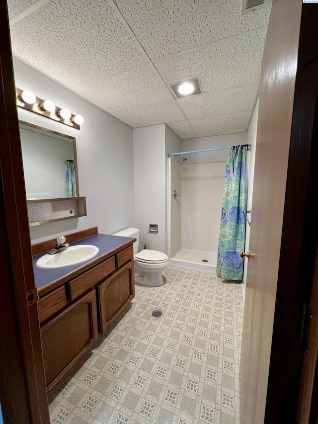 bathroom with vanity, a paneled ceiling, toilet, and walk in shower